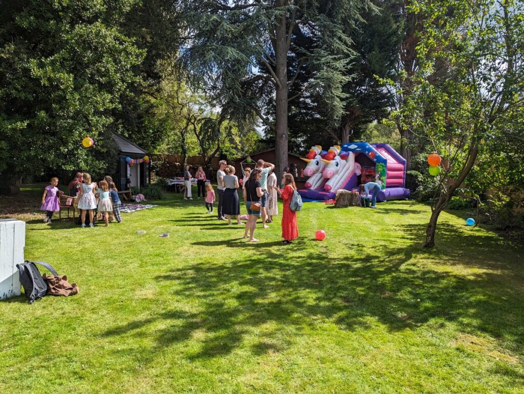 Fête d'anniversaire pour enfants dans un jardin privatisé avec château gonflable et pelouse ensoleillée