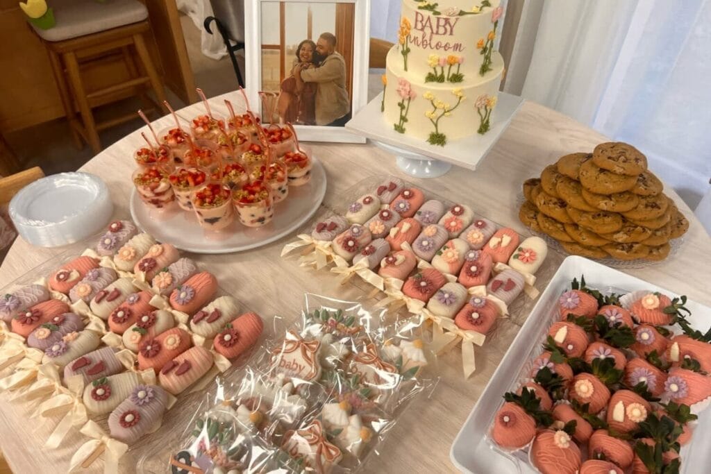 Buffet de desserts pastel avec gâteau, biscuits décorés, fraises enrobées et cake pops.