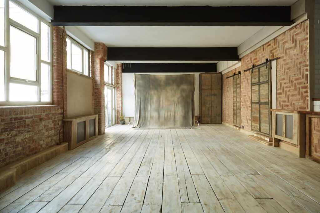 Loft d'entrepôt lumineux avec murs en briques rouges, parquet clair et toile de fond pour shooting