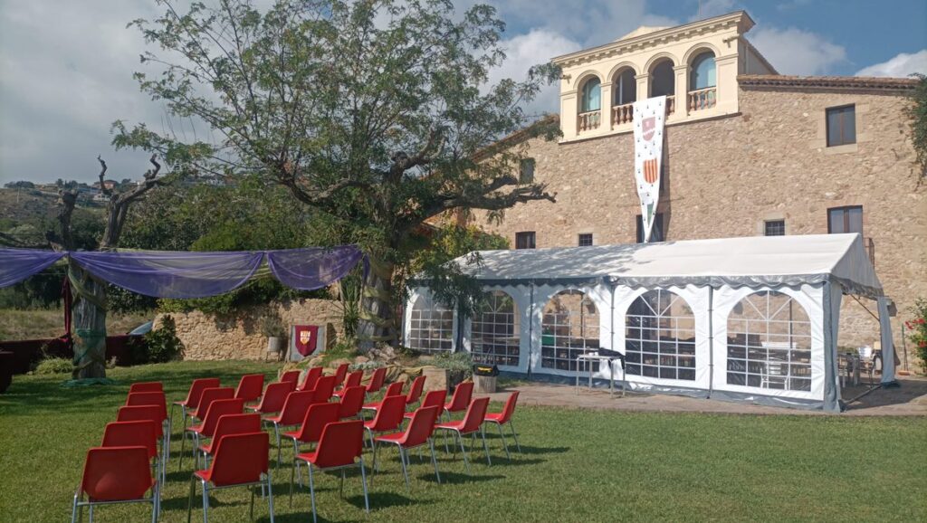 Jardin d'un domaine en pierre avec chapiteau et chaises disposées en rangées pour une cérémonie en extérieur