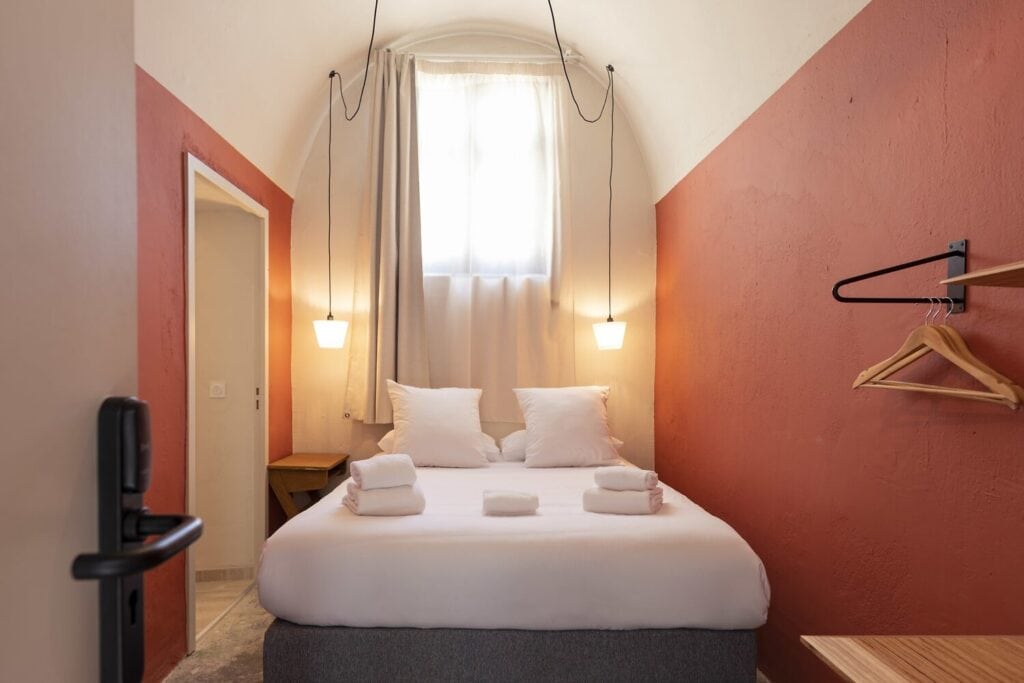 Balise alt	Chambre voûtée de l’Hôtel La Prison à Béziers, avec fenêtre haute et murs terracotta