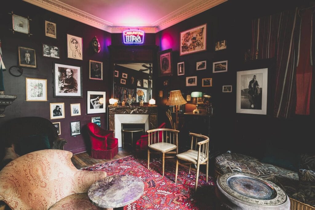 Salon sombre du bar Le 1905 à Paris, décoré comme un cabinet de curiosités avec tapis et fauteuils
