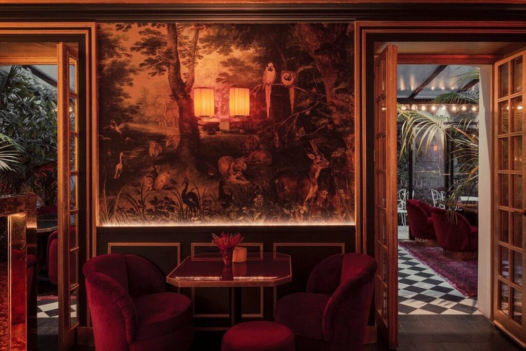 Salon rouge du Très Particulier à Montmartre, ouvert sur une verrière végétale au sol en damier