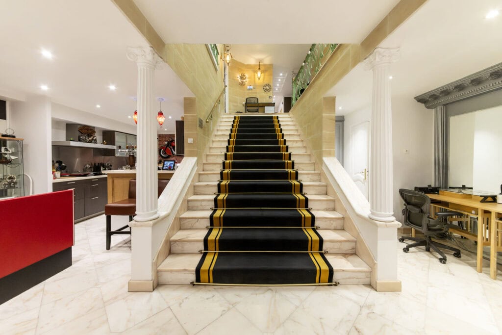 Grand escalier en marbre avec tapis noir et or, colonnes corinthiennes et hall néoclassique privatisable pour événement
