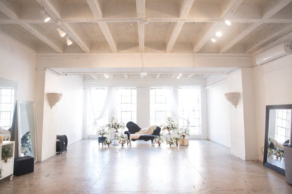 Loft blanc baigné de lumière naturelle avec grandes fenêtres, hauts plafonds et espace dégagé
