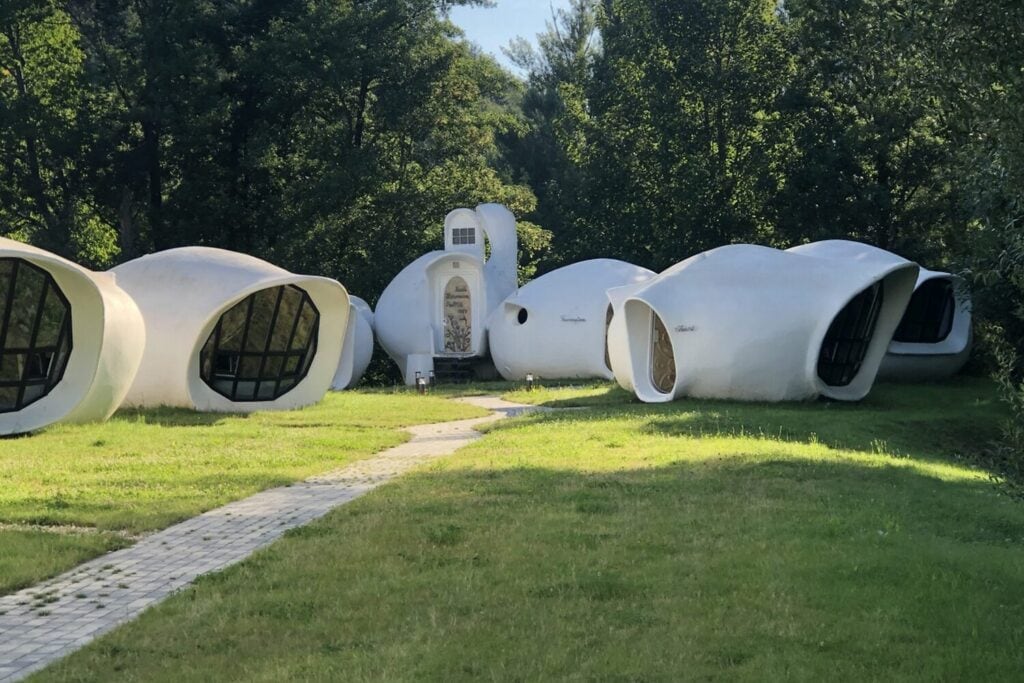 Balise alt	Maisons-bulles blanches du Motel de l’Eau Vive alignées dans un jardin arboré
