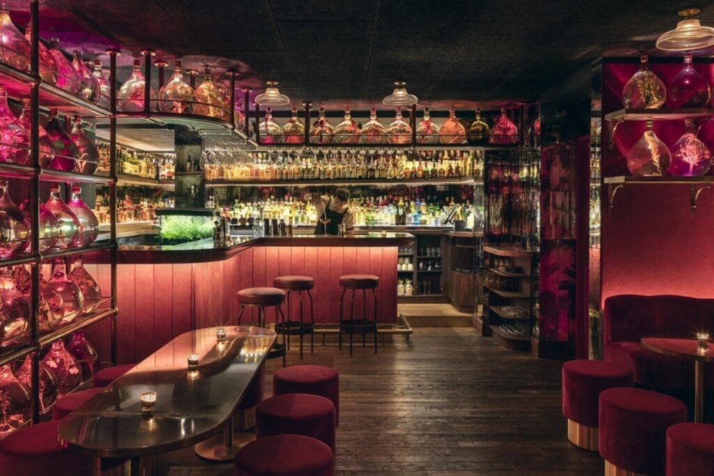 Salle rose du No Entry sous Pink Mamma, entourée de dames-jeannes fleuries et de banquettes en velours