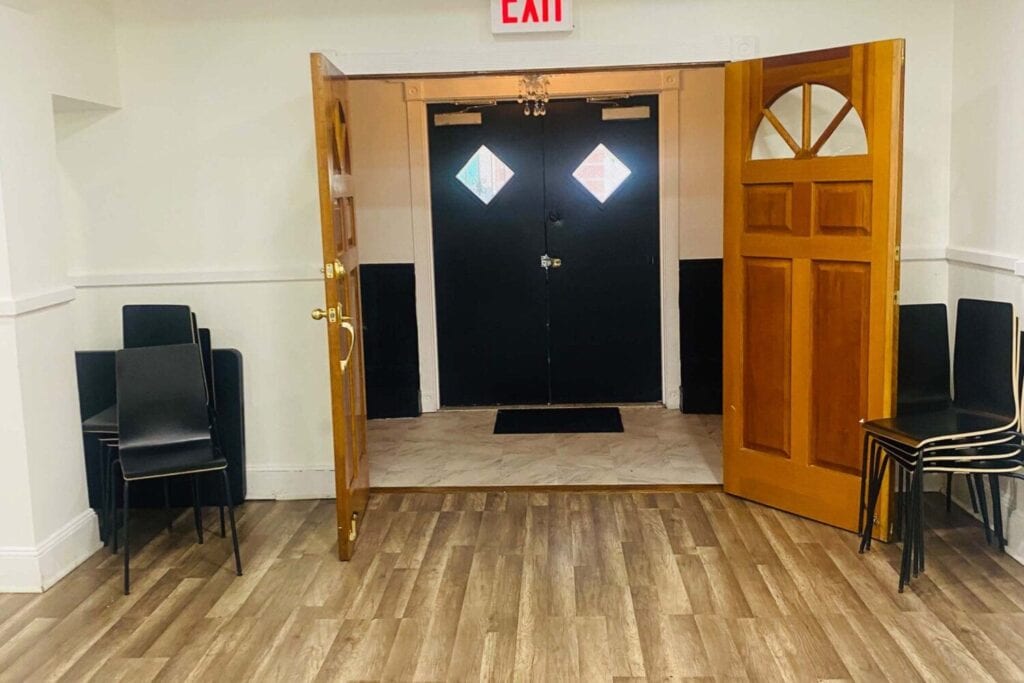 Portes doubles encadrées par plusieurs piles de chaises dans une salle lumineuse.