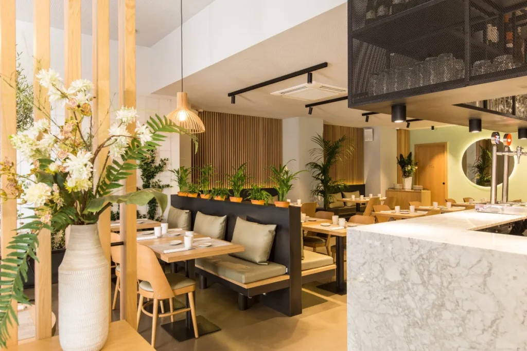 Vue d'ensemble d'un restaurant privatisable avec banquettes, cloisons en bois et composition florale au premier plan