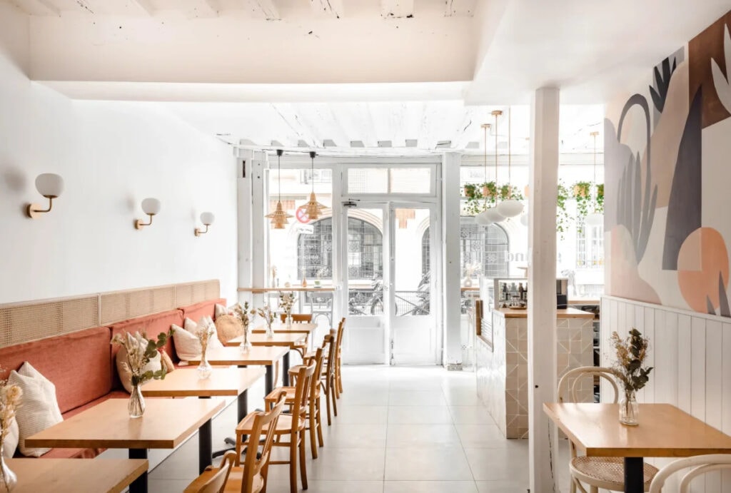 restaurant lumineux avec fauteuils roses et tables en bois