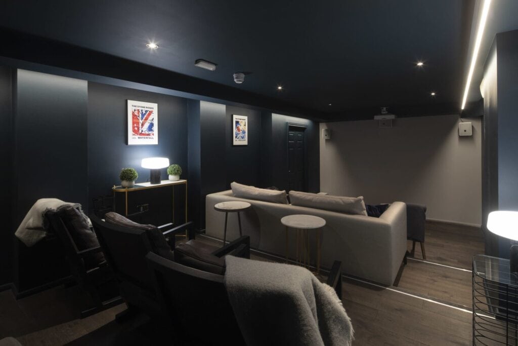 Salle de cinéma privée avec canapés, fauteuils et éclairage tamisé.