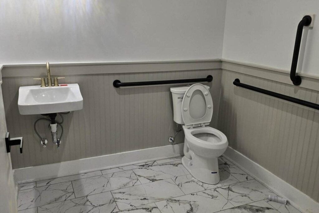 Sanitaires accessibles avec lavabo, toilettes et barres d'appui murales.