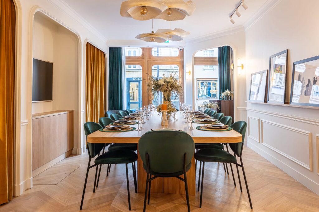 Salle privative dans un restaurant parisien avec table dressée pour 12 personnes, chaises en velours vert et parquet en chevrons