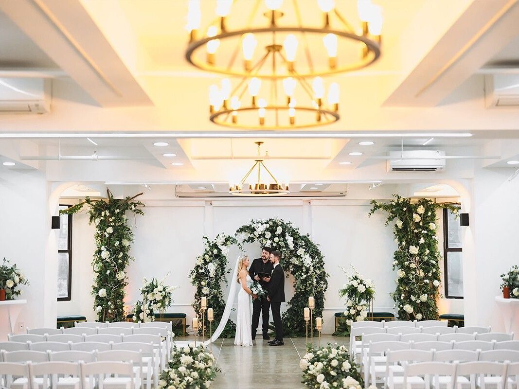 Couple standing at indoor wedding altar at Chicago wedding with florals and white chairs