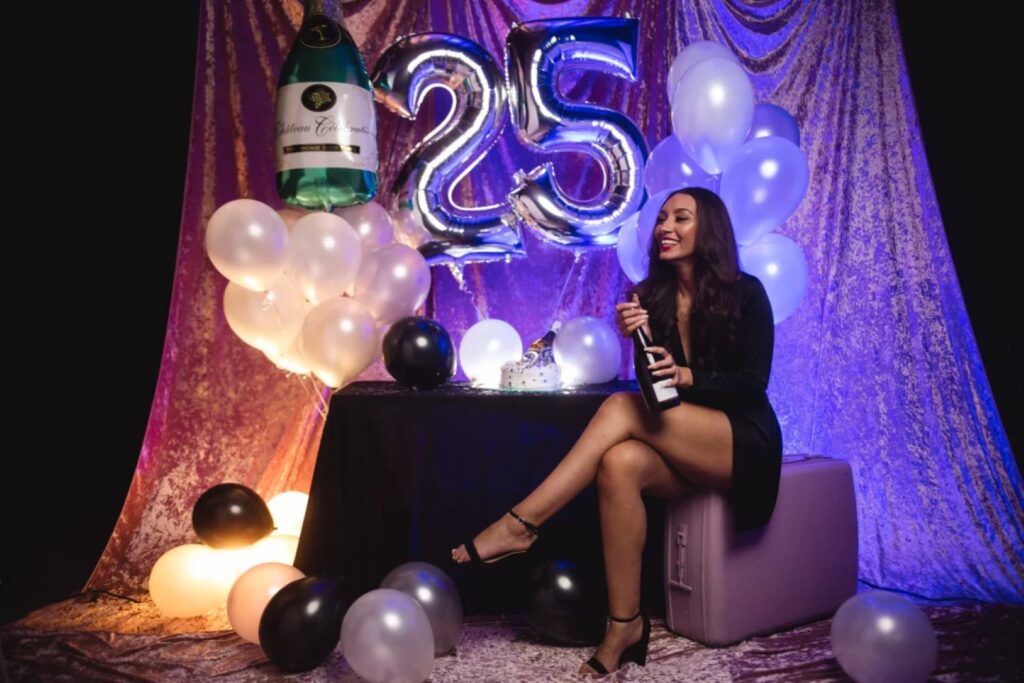 woman with balloons opening a bottle of champagne