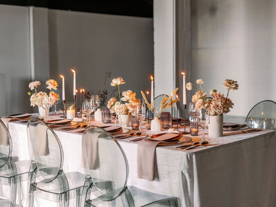 Clear chairs and simple white walls, table with florals and candles at New York wedding venue