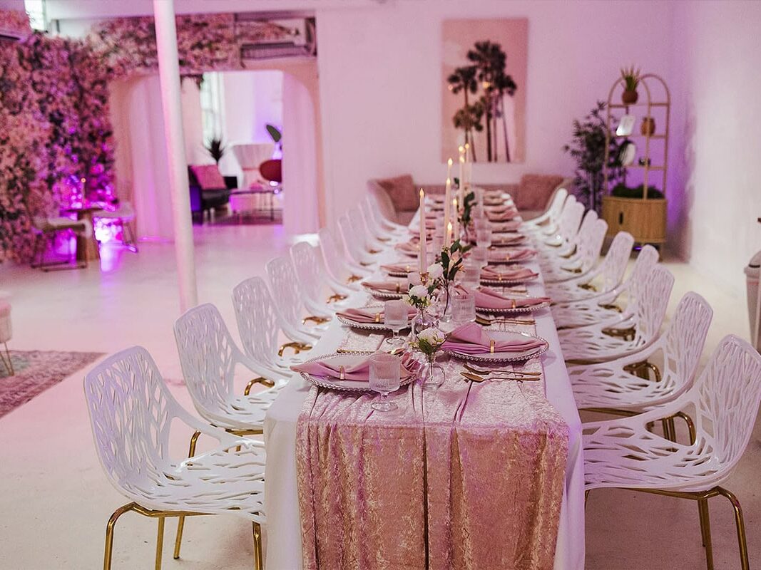 Pink glowy interior with long table and chairs set up by Chicago wedding planner