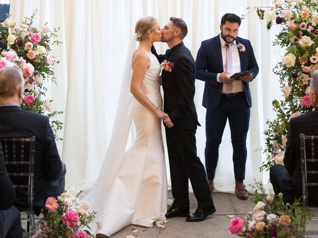 Couple kissing at Atlanta wedding ceremony surrounded by pink florals
