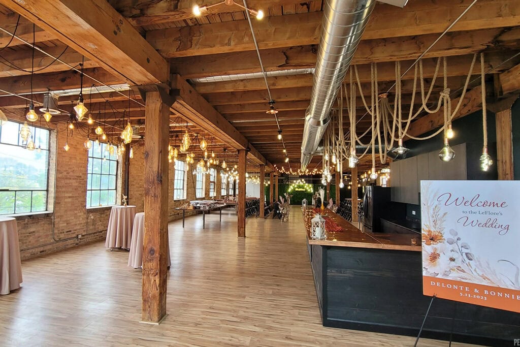 Indoor wooden Dallas wedding venue with string lights, pillars, and greenery