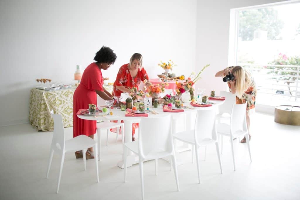 A photographer taking a picture of a table setup in a bright venue