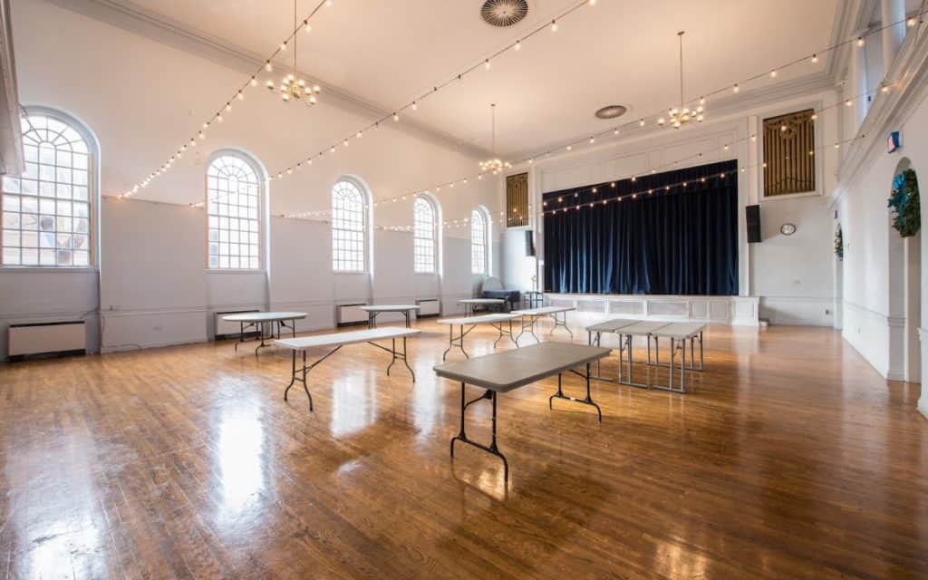 an all-white event space with tables and a stage