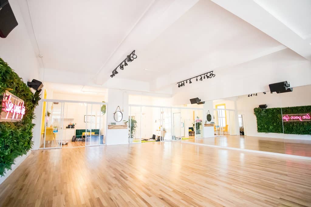 a dance studio with high ceilings, mirrored walls, and wooden floors