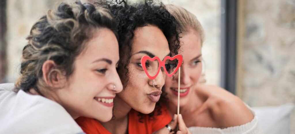 Three women pose with fake heart glasses for photo