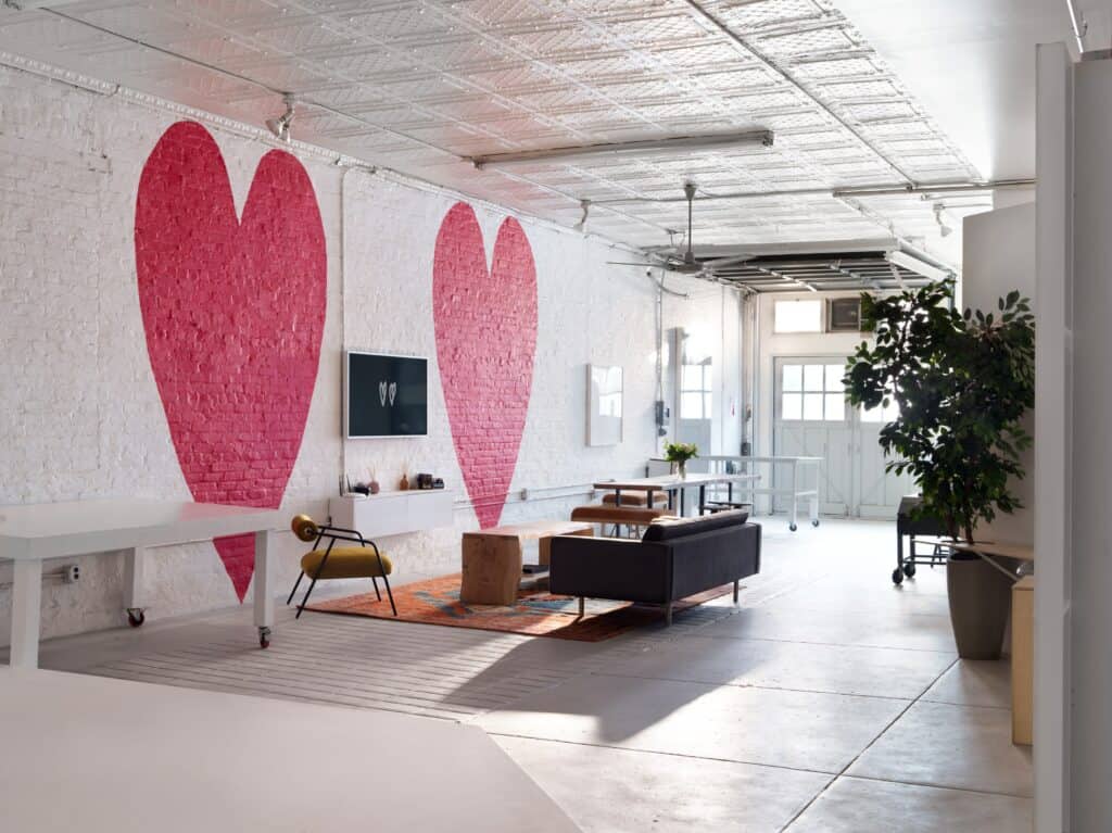 an all-white studio with large red painted hearts