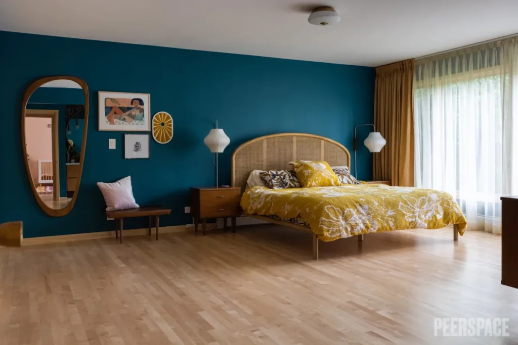 A contemporary bedroom with dark turquoise walls and a bed with yellow bedding