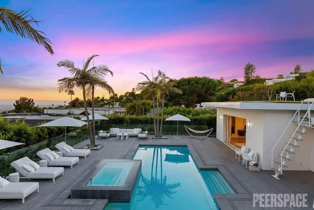 A backyard of a house with a pool, chairs, and a hot tub