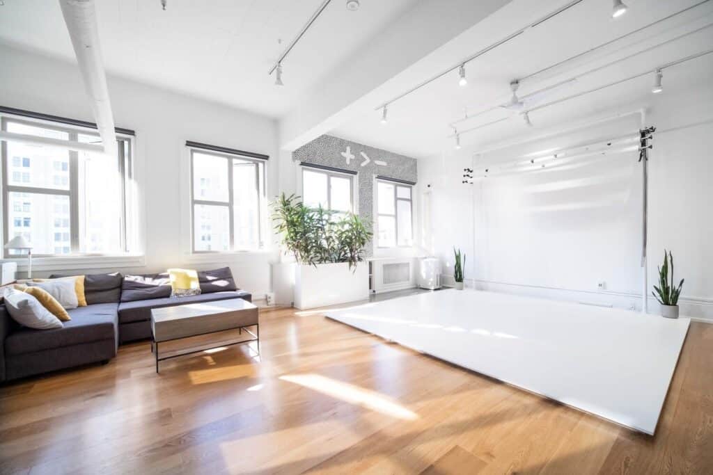 A daylight studio with a white backdrop and grey sectional couch