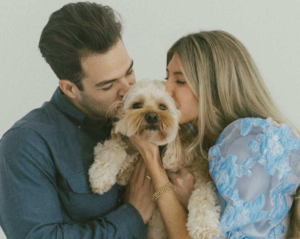 Couple kissing their dog at a dog party