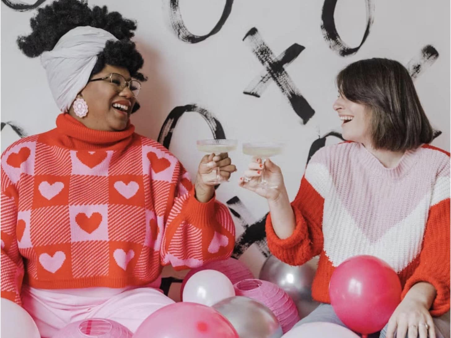 Women in Galentines clothing cheersing around pink and white balloons