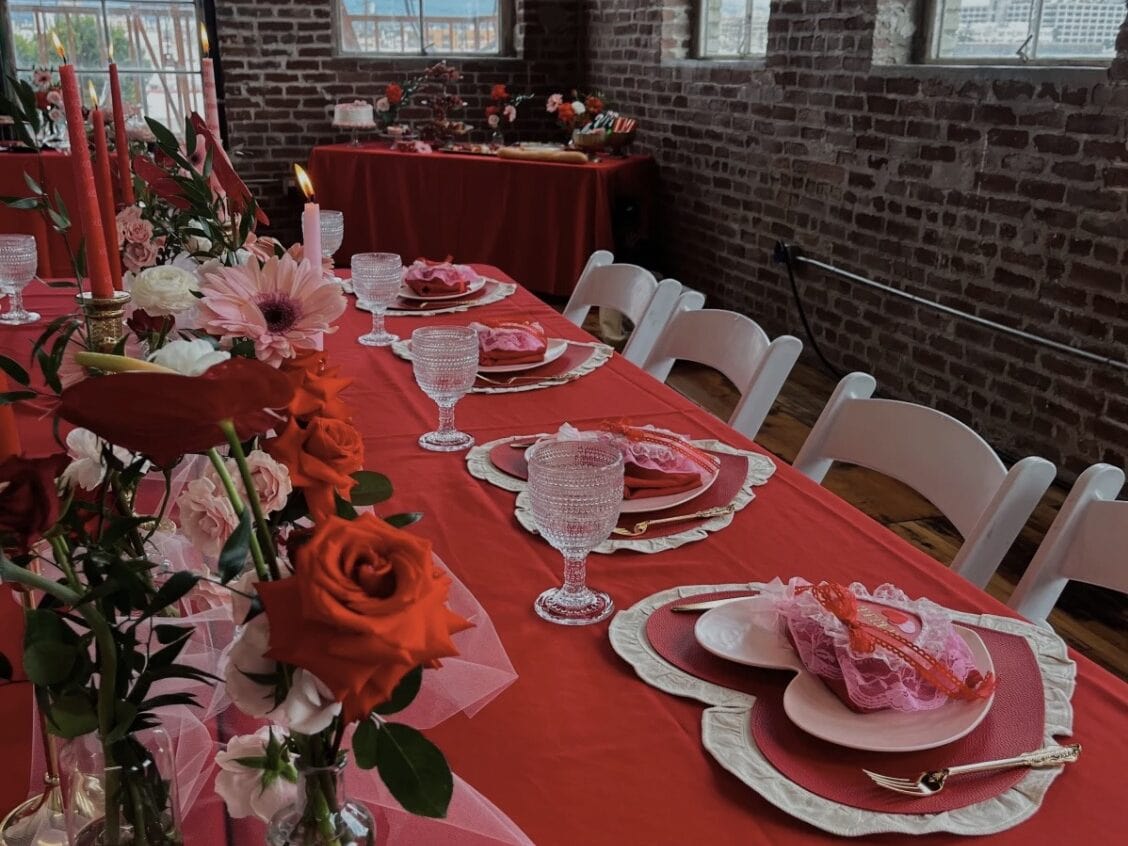 Galentines themed table with red tablecloth, roses, and heart plates