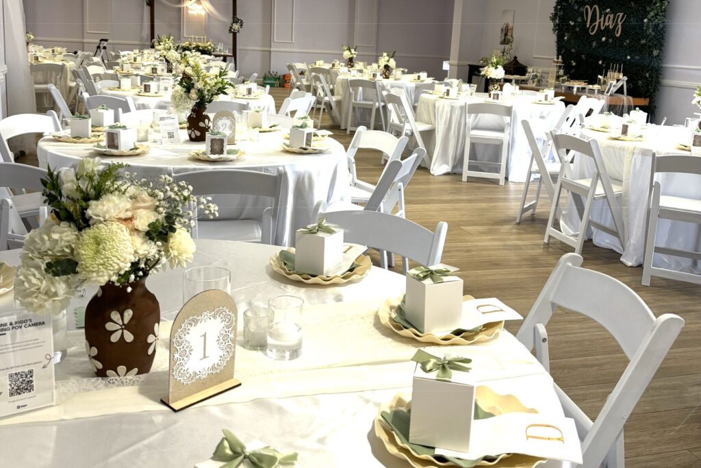Indoor wedding setup with white tablecloth, table numbers, plating for Charlotte wedding