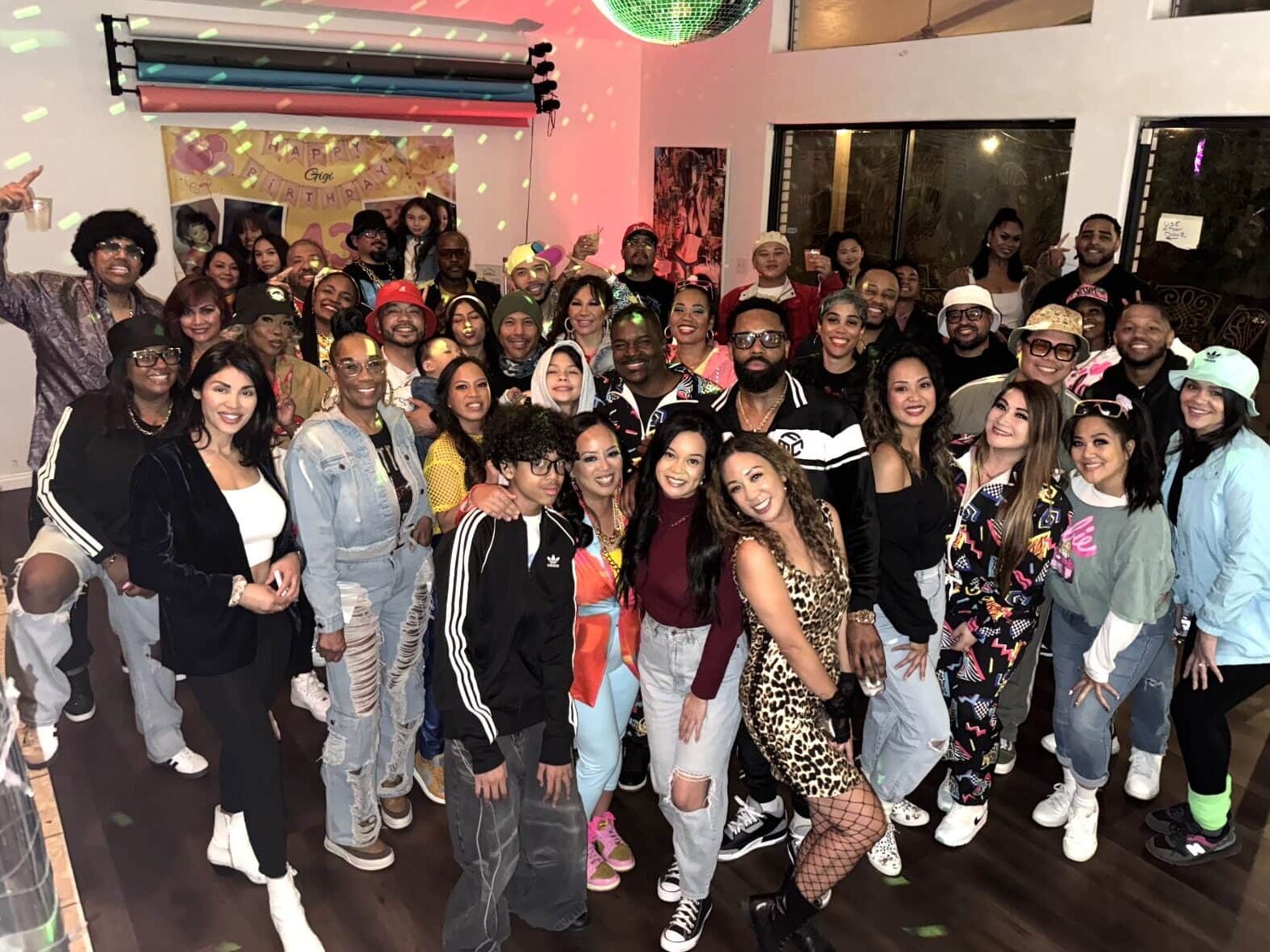 Large group of people celebrating indoor birthday party with disco ball