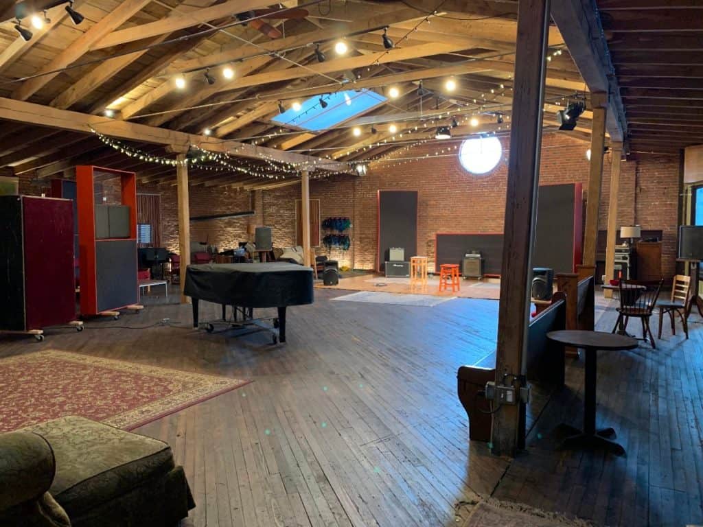 A rustic event space with exposed brick walls, a piano, and chairs