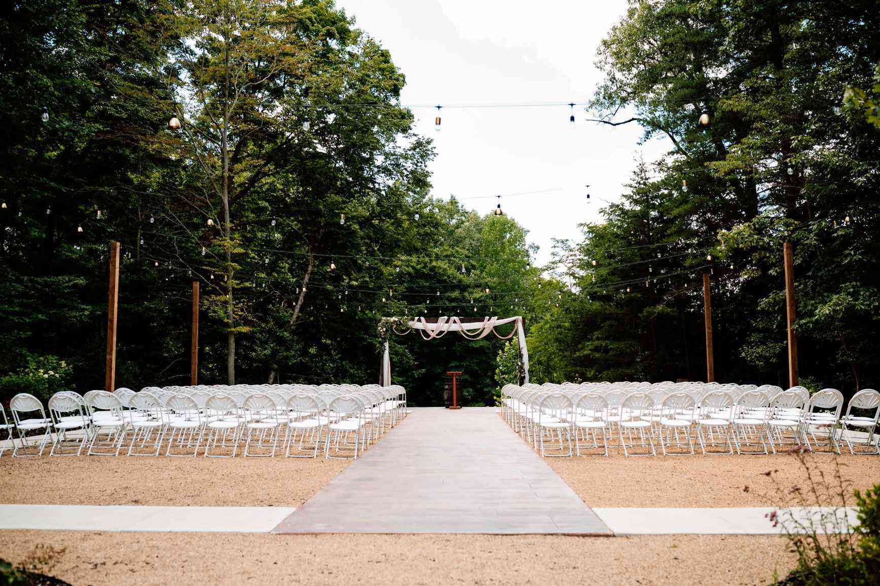 Outdoor wooded ceremony aisle with arch styled by Wedding Planners in Lexington