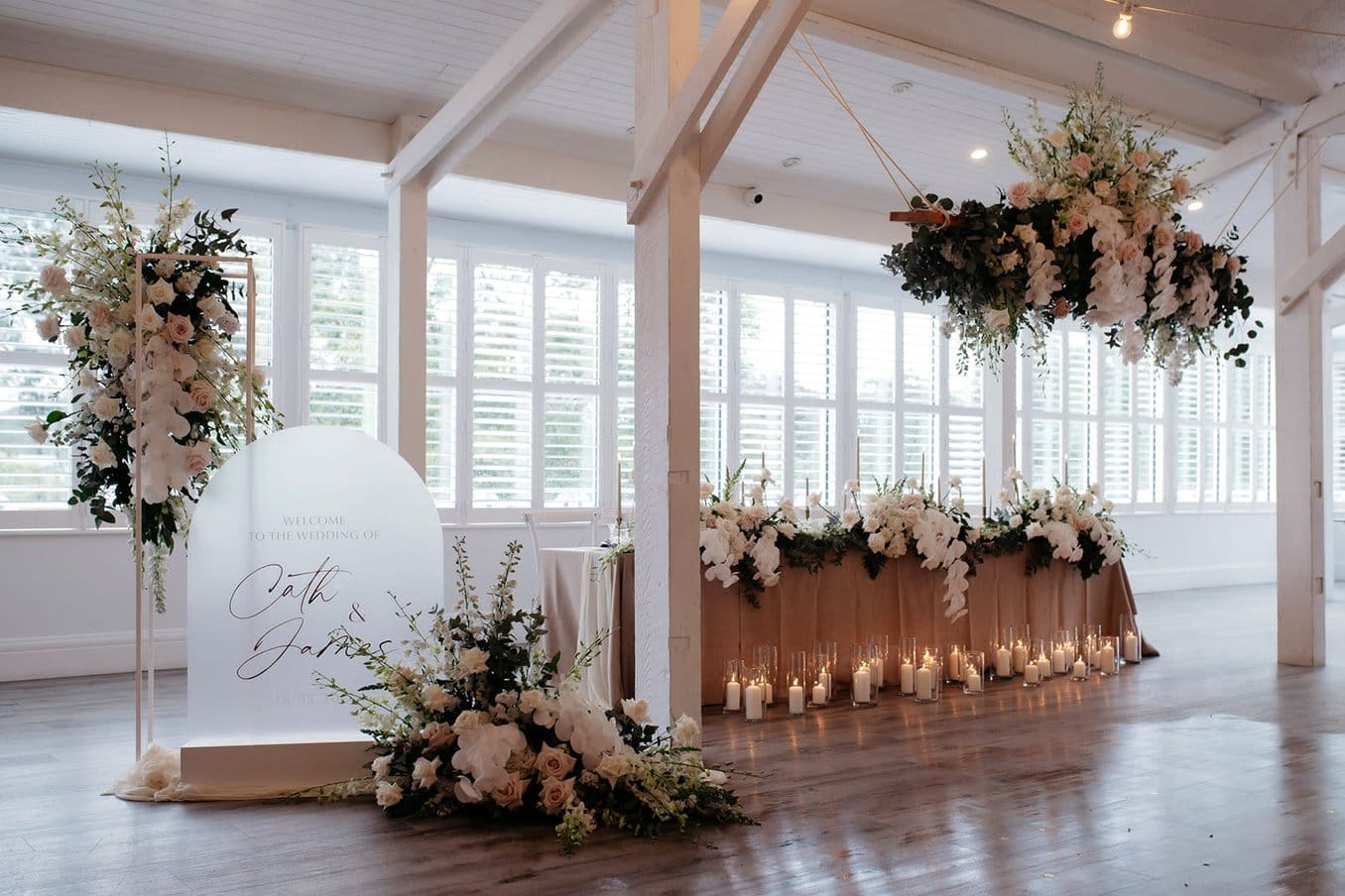 Candlelit indoor Maine wedding ceremony aisle with floral arch decoration