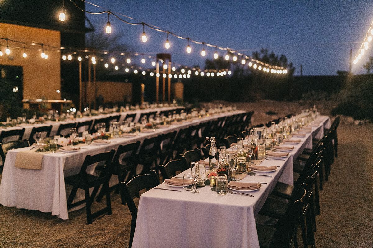 Elegant evening wedding reception dinner table set under string lights