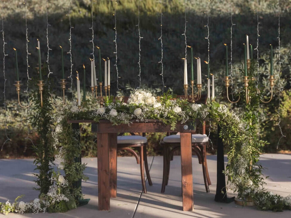 Wooden table with cascading greenery and candles done by New Orleans wedding planner
