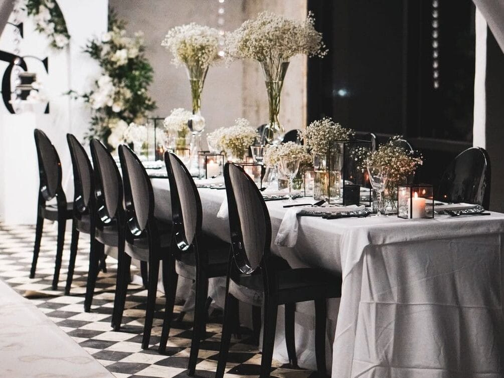White table and black chairs with florals at wedding planned in New Orleans