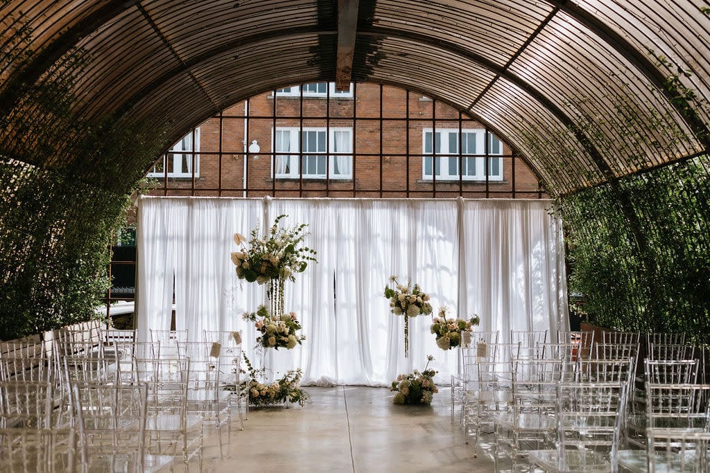 Industrial Pittsburgh wedding venue with arched glass structure and hanging floral installations