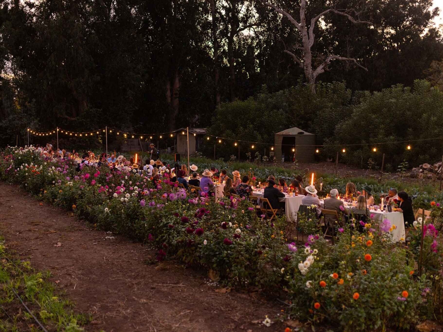 Nighttime photo of wedding guests seated at long table at outdoor garden Washington wedding