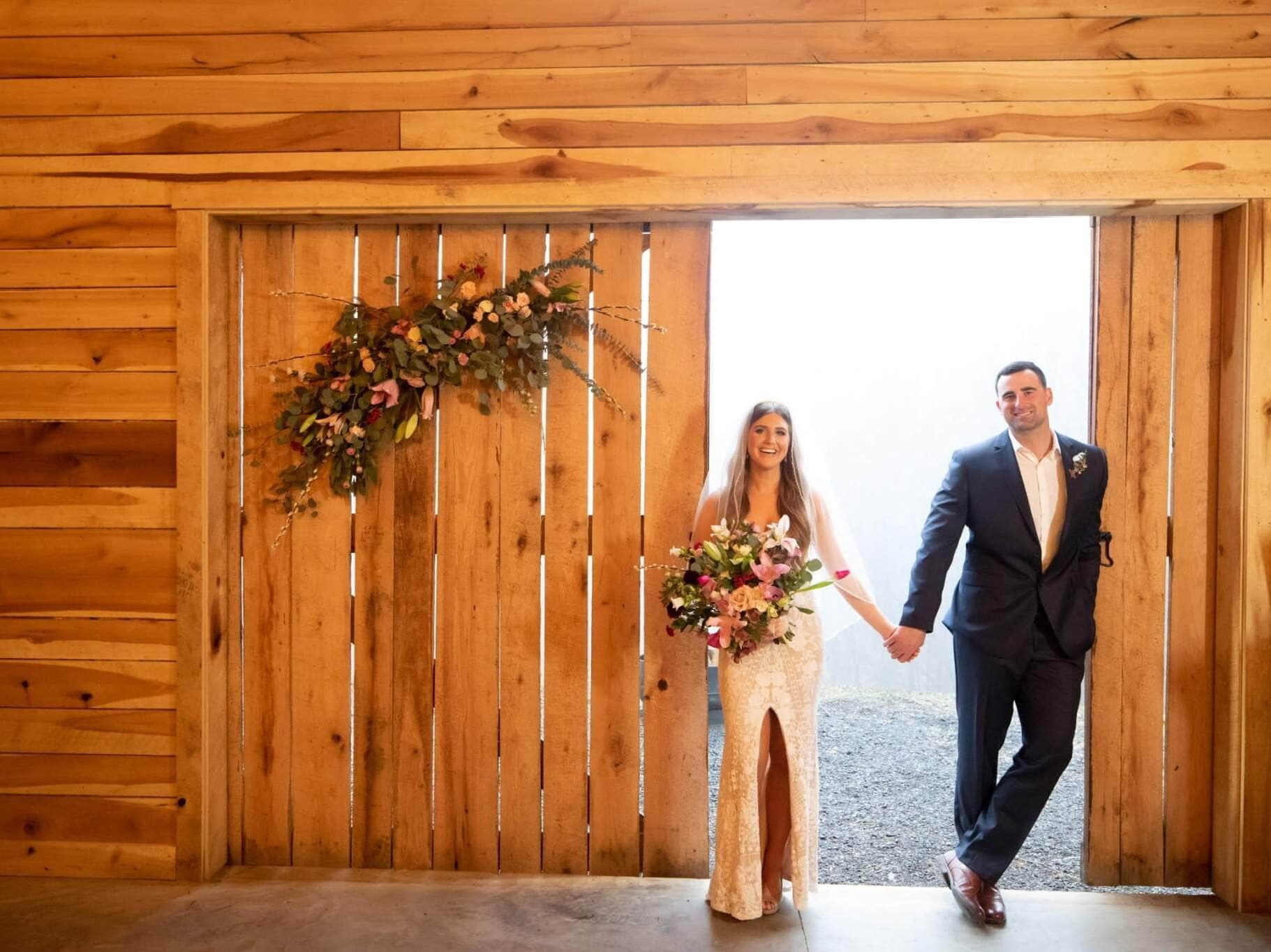 Couple holding hands in front of wooden door with flowers at wedding planned in Washington
