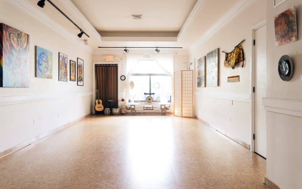 A naturally lit, open-space room filled with artwork and instruments