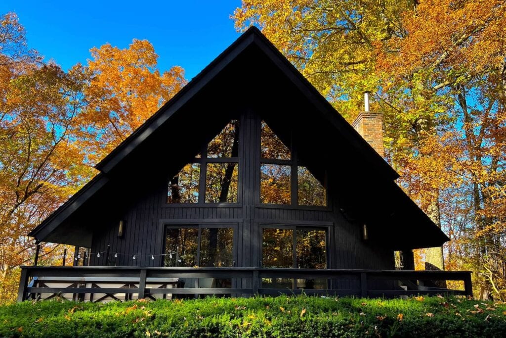 Exterior of an A-frame house in upstate New York with fall foliage in the background