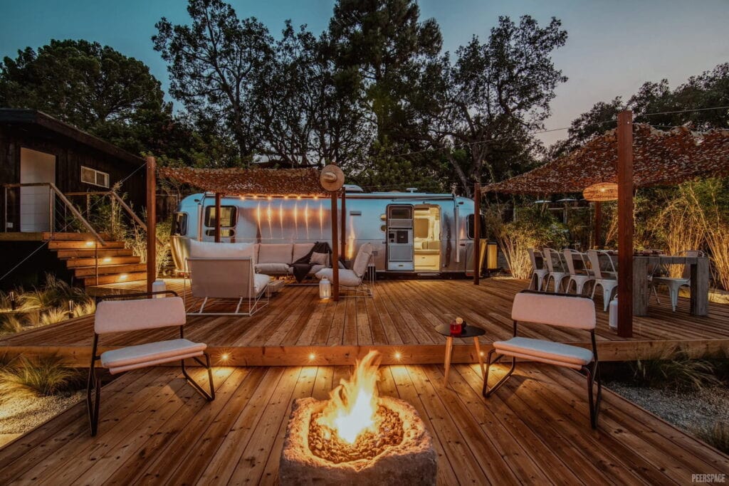 Luxury Airstream setup with dining and lounging areas outside under pergolas