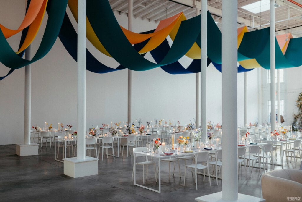 An airy warehouse event space decorated with colorful fabrics and flowers