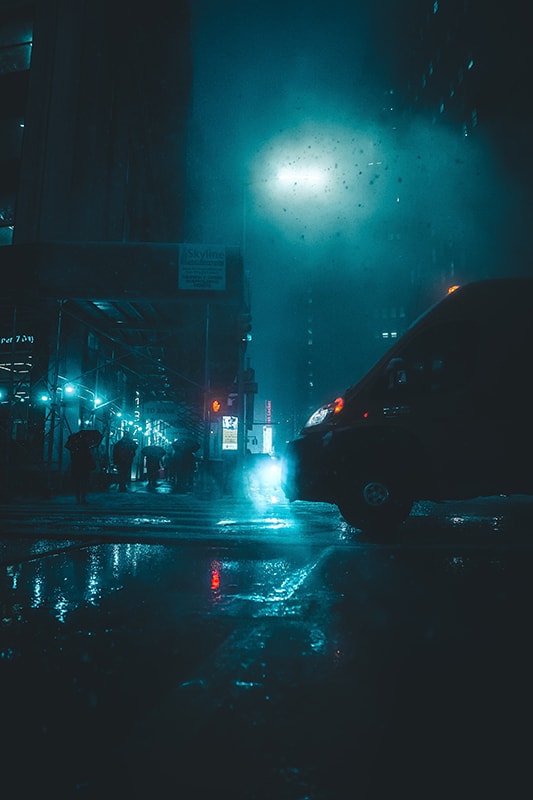 Rain falling on city street at night